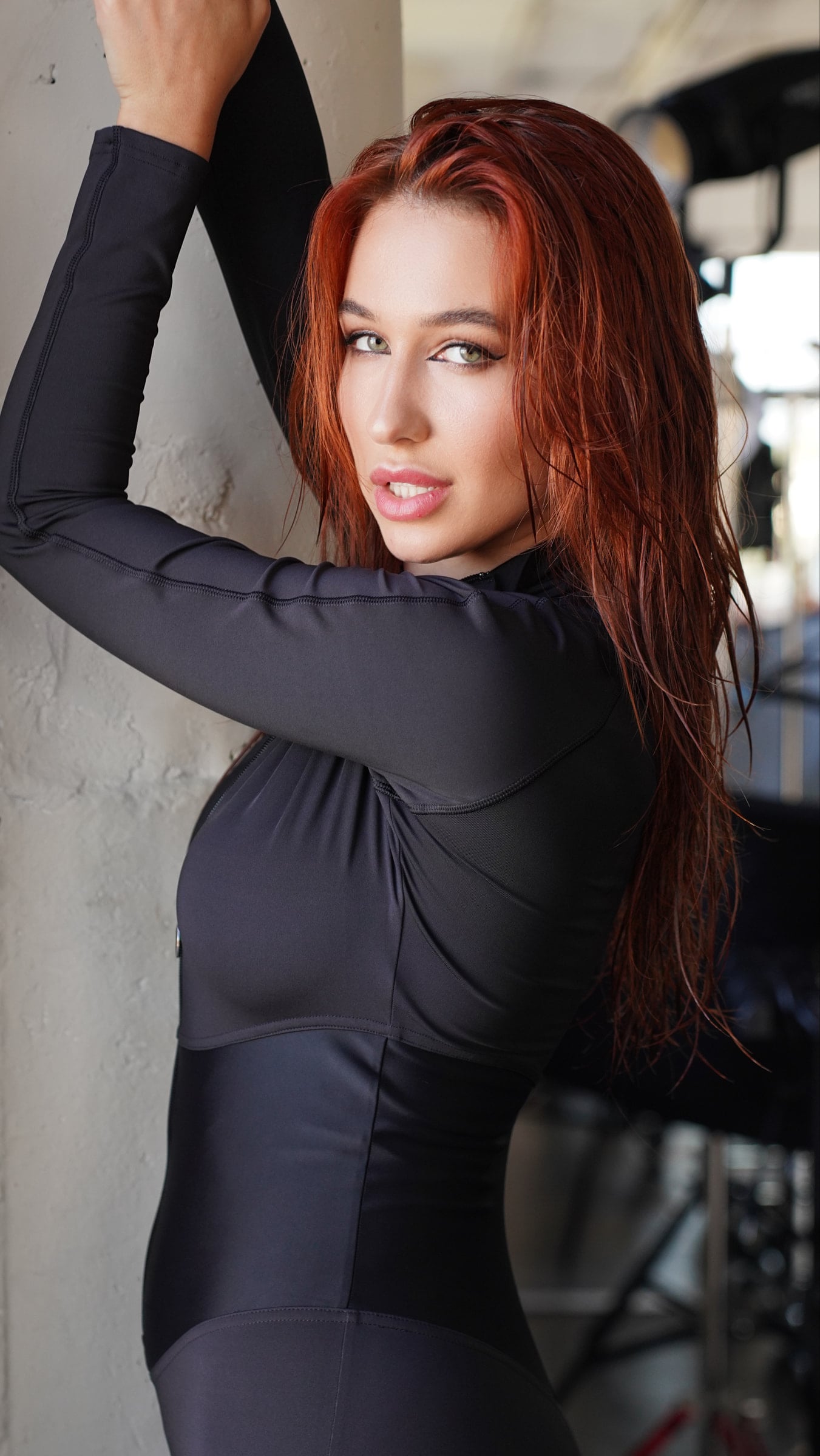 Iryna Vyacheslavivna posing with raised arms in a fitted black catsuit