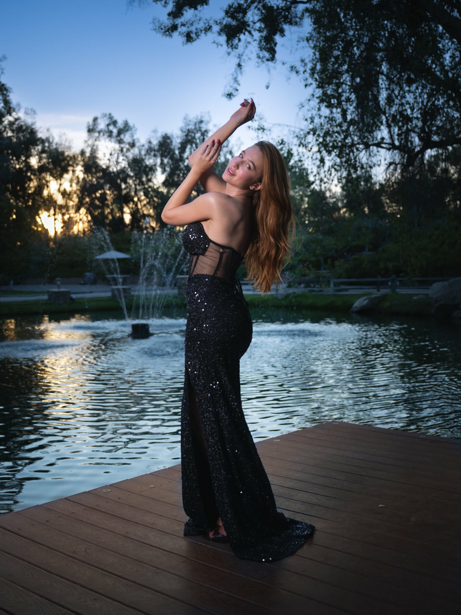 Iryna Vyacheslavivna posing in profile in a black sequin gown beside a lake