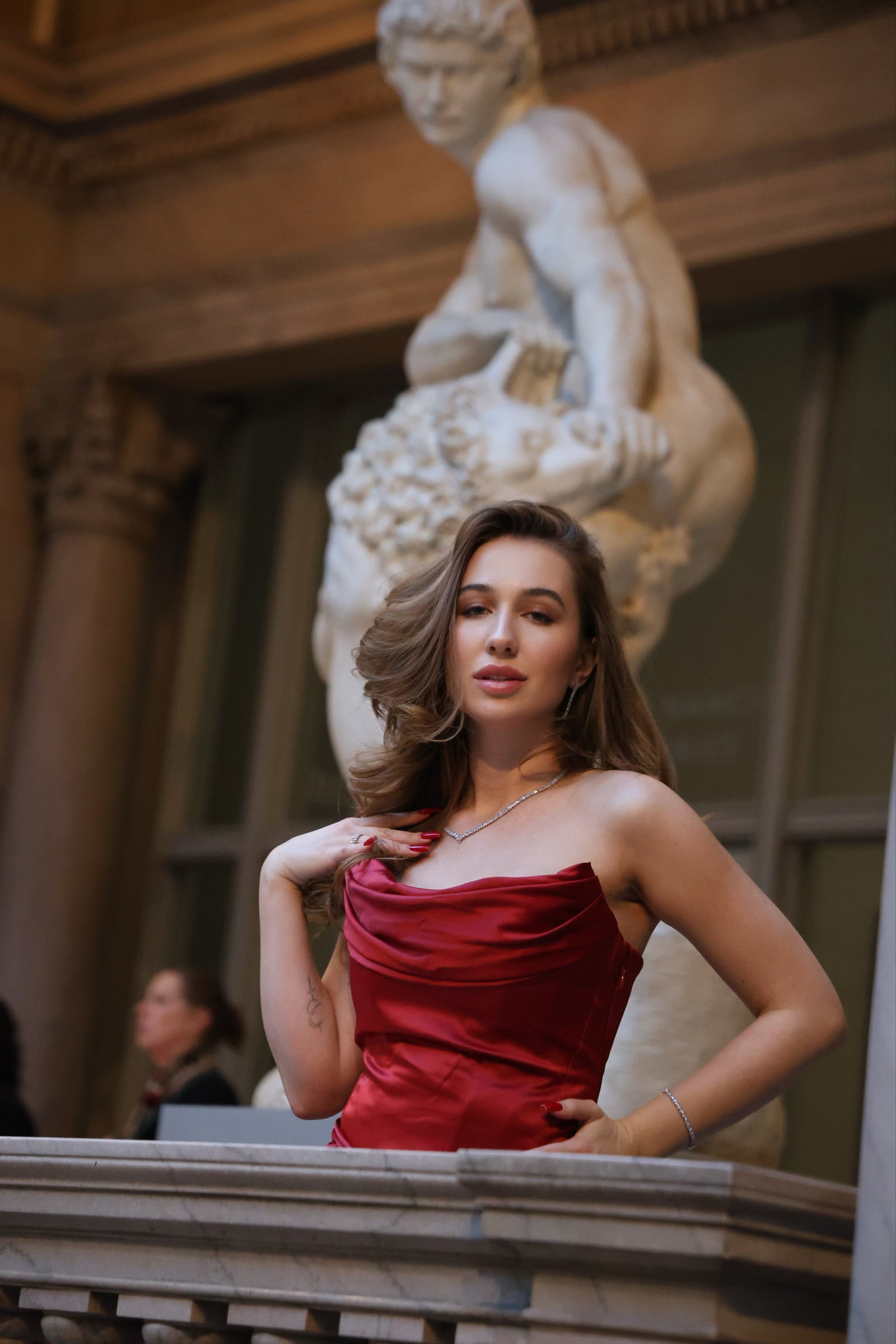 Iryna Vyacheslavivna posing beside a stone balcony in a red satin dress